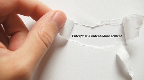 Photo of a hand peeling back paper to reveal the typewritten words Enterprise Content Management